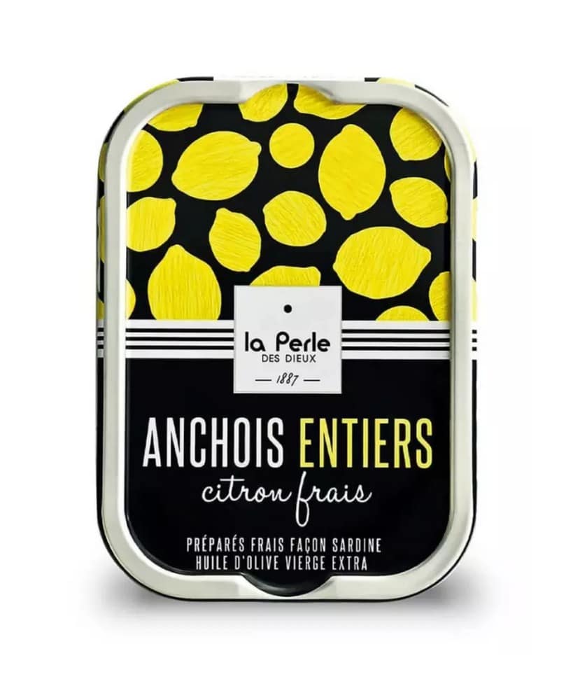 Svart och citrongul konservburk från La Perle des Dieux med texten "ANCHOIS ENTIERS citron frais". Burken har ett mönster av gula citroner mot svart bakgrund. Ansjovis (115g).