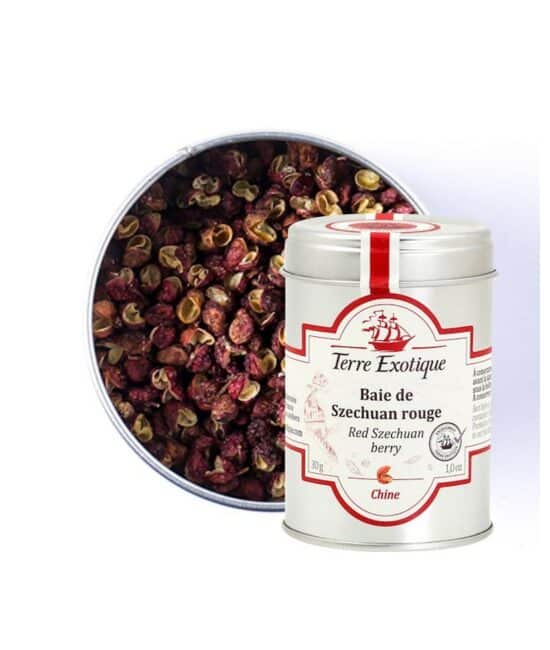 Burk med Terre Exotique Sichuanpeppar (30g). De röda och bruna pepparkornen (skalen) ligger på en sked bredvid en wokpanna, färsk ingefära och koriander, i en asiatisk köksmiljö.