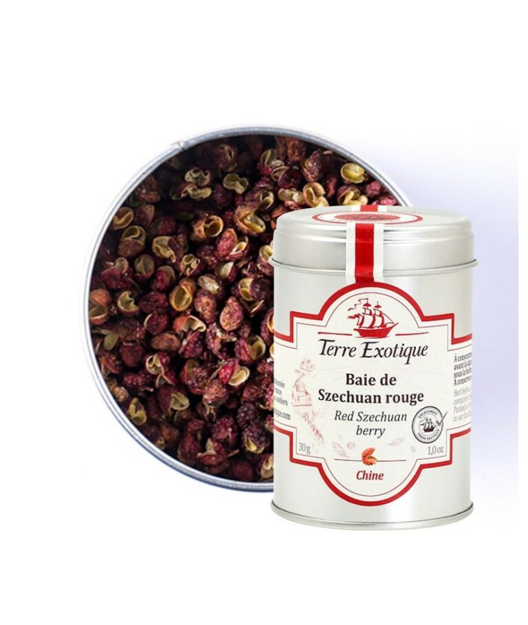 Burk med Terre Exotique Sichuanpeppar (30g). De röda och bruna pepparkornen (skalen) ligger på en sked bredvid en wokpanna, färsk ingefära och koriander, i en asiatisk köksmiljö.