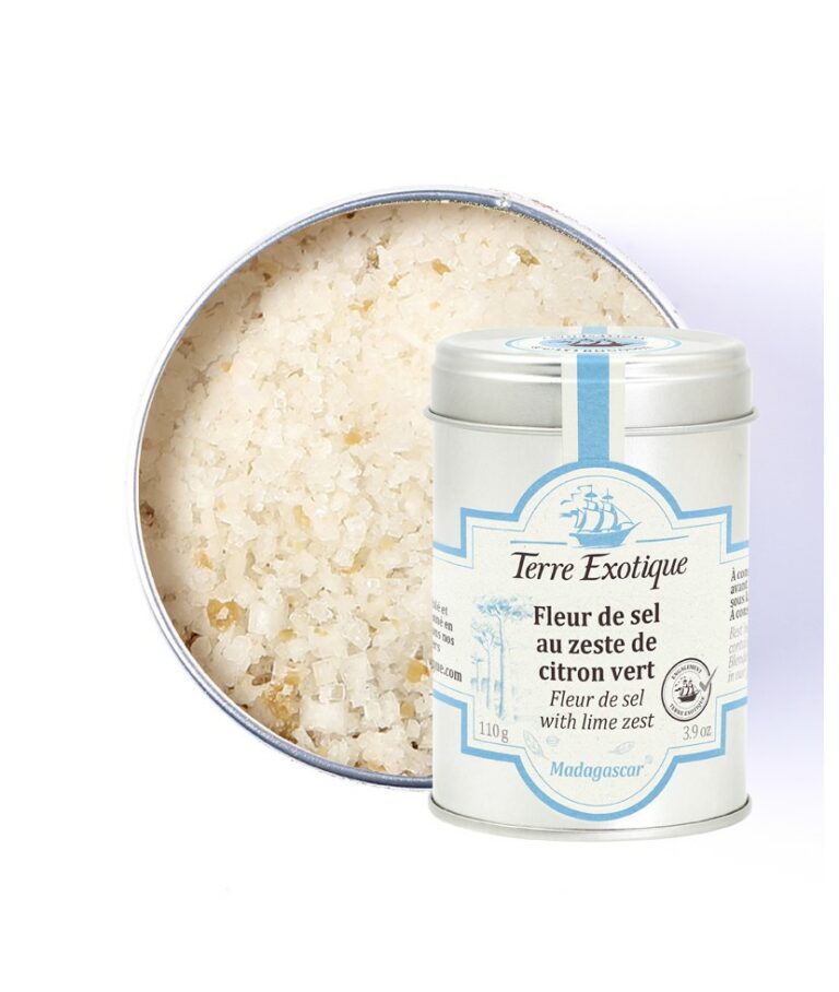 Burk med Terre Exotique Lime-salt (110g). De vita och gröna saltkristallerna ligger på en sked bredvid färska limeklyftor, en bit ceviche eller lax och en cocktail. Ljus och fräsch matlagningsmiljö.