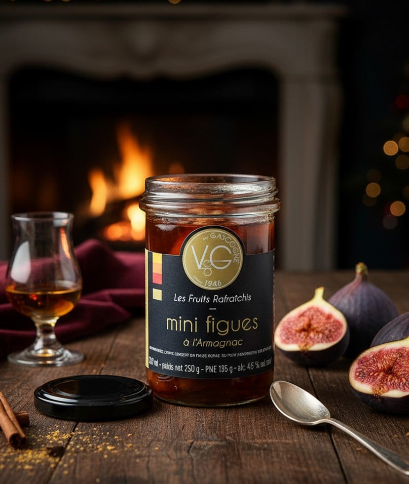 Burk med minifikon konserverade i Armagnac, arrangerad med färska fikon, kanelstänger, en sked och ett glas Armagnac framför en öppen spis och en julgran.